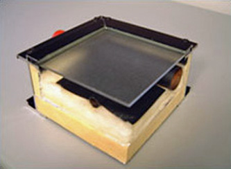Photo of a mid-temperature flat plate solar collector showing cover glass, insulation, copper absorber plate, and flow passages
